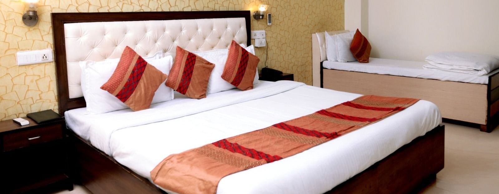 A luxurious hotel room with a king-size bed, golden accent wallpaper, warm lighting, and a modern aesthetic - Hotel Diamond Inn, Chandigarh