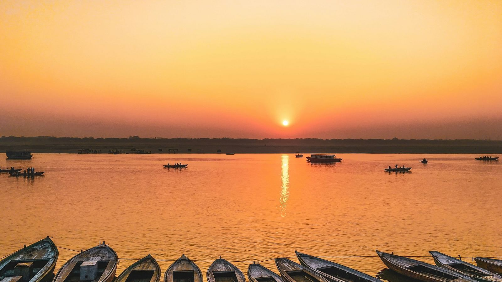 view of the lakes at sunset with boats placed on the shore 