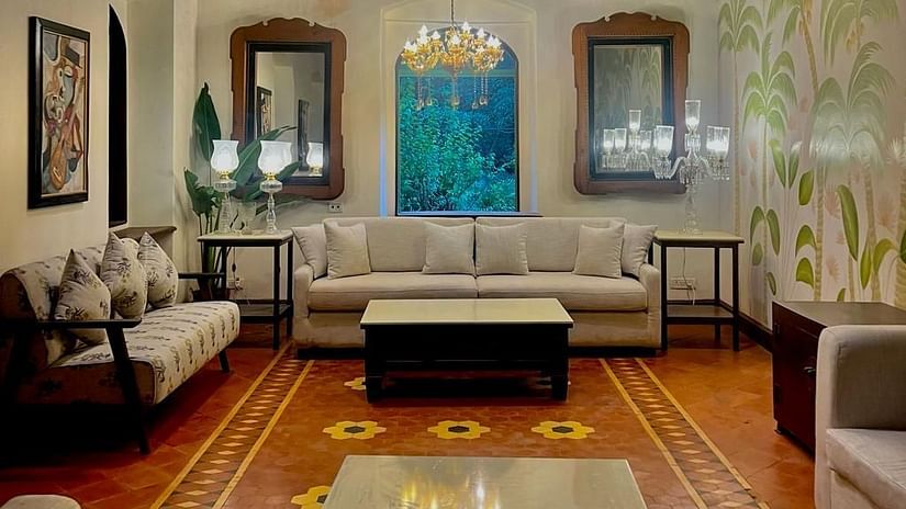 An image of a living area with sofas and centre tables, photo frames on the wall, tables on each corners where decorative items are placed - Lamrin Ucassaim Hotel, Goa