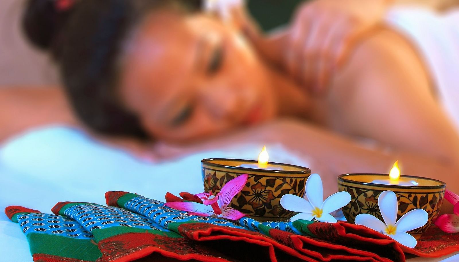 Woman in a spa with two lighted candles and flowers at Ocean Spray Puducherry 