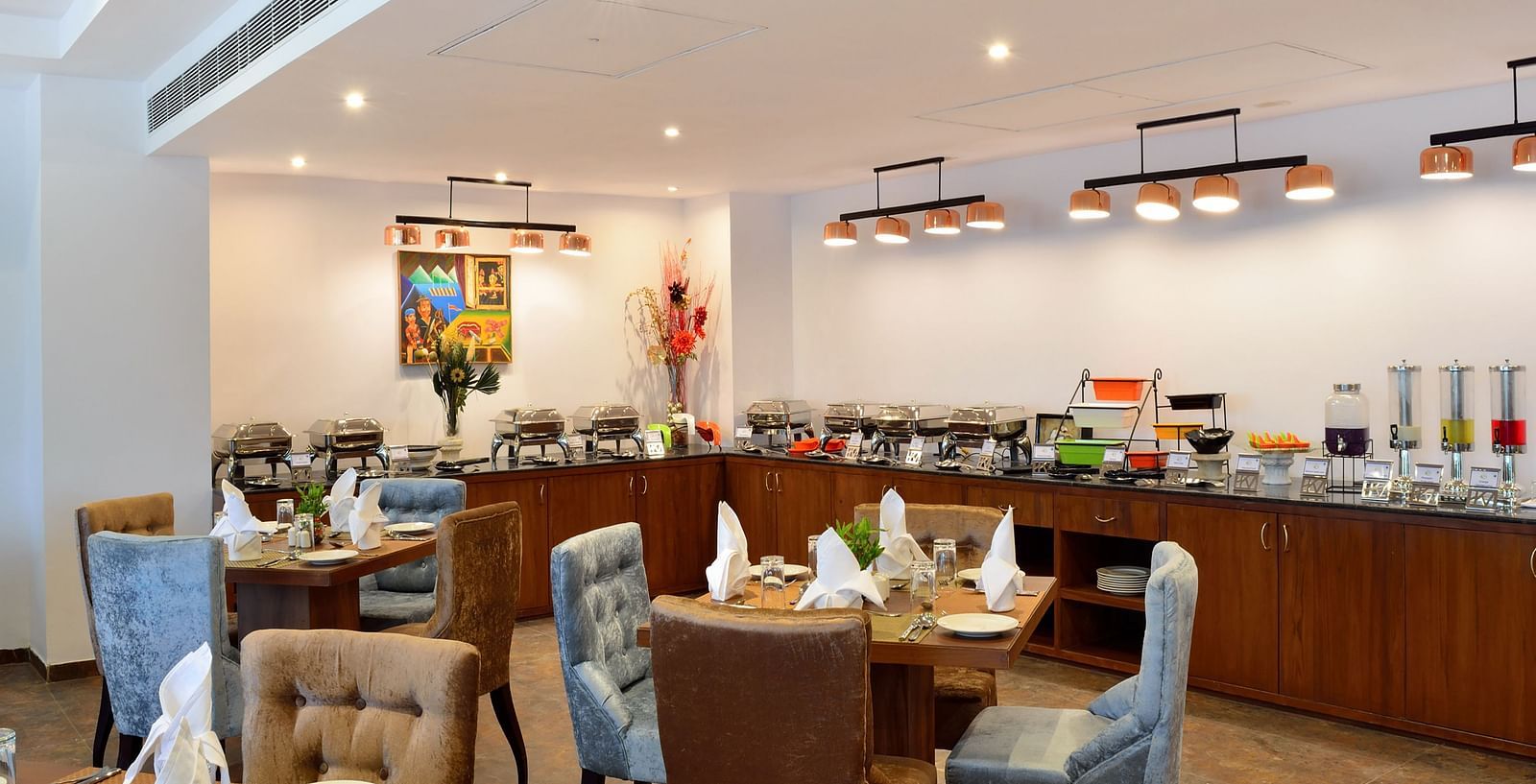 A well-lit dining area with tables and chairs, set for a meal. - Bamboo Saa Resort & Spa, Udaipur