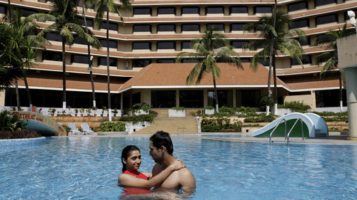 Two people relaxing in a Swimming Pool with a building in the background.