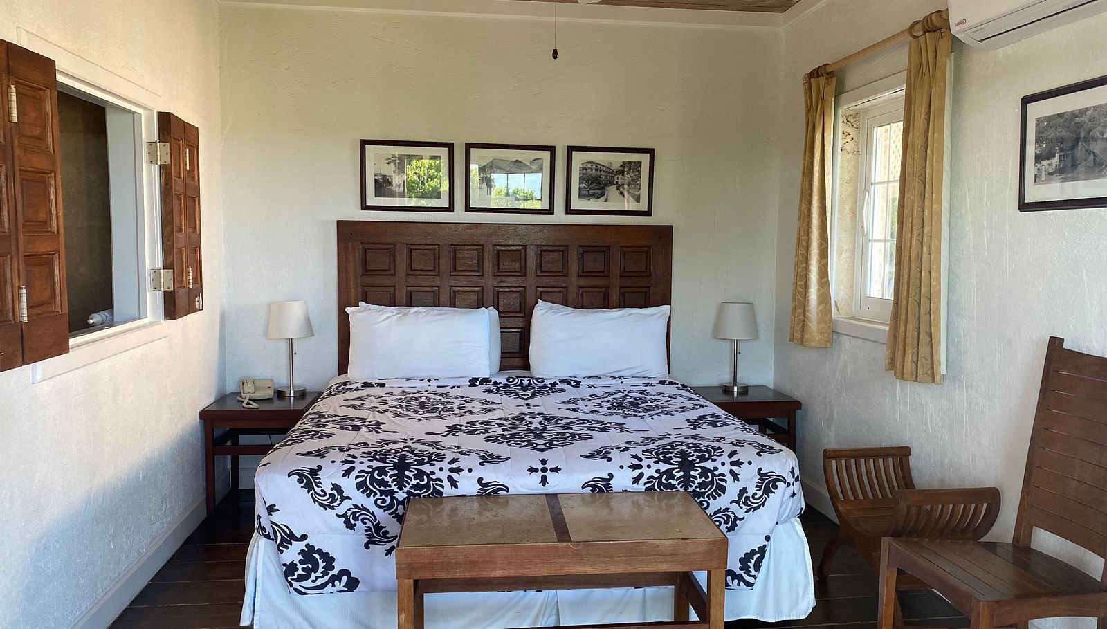Bedroom with a large bed, ceiling fan, table, chair, and framed art on the wall | A Stone's Throw Away