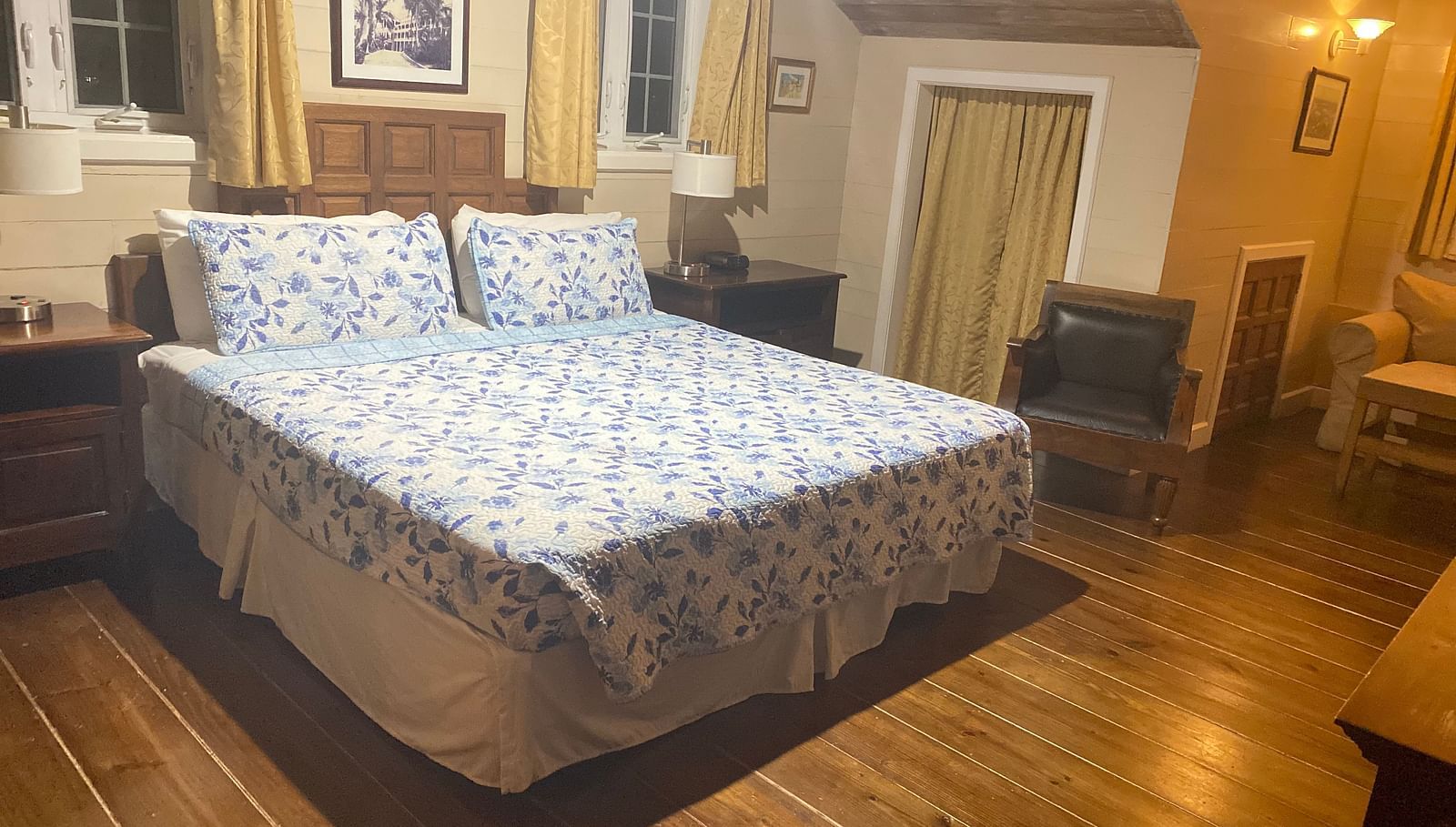 Bedroom with a bed, wooden floor, wooden furnishings, and beige walls | A Stone's Throw Away