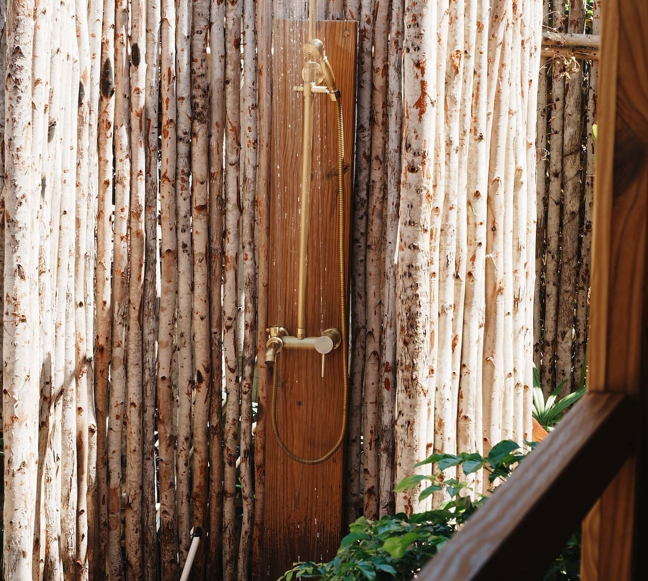 A private outdoor shower area at the Peaceful Tent in WoCAL Retreat Ke Ga, enclosed by vertical wooden branches, creating a serene setting for bathing under open skies.