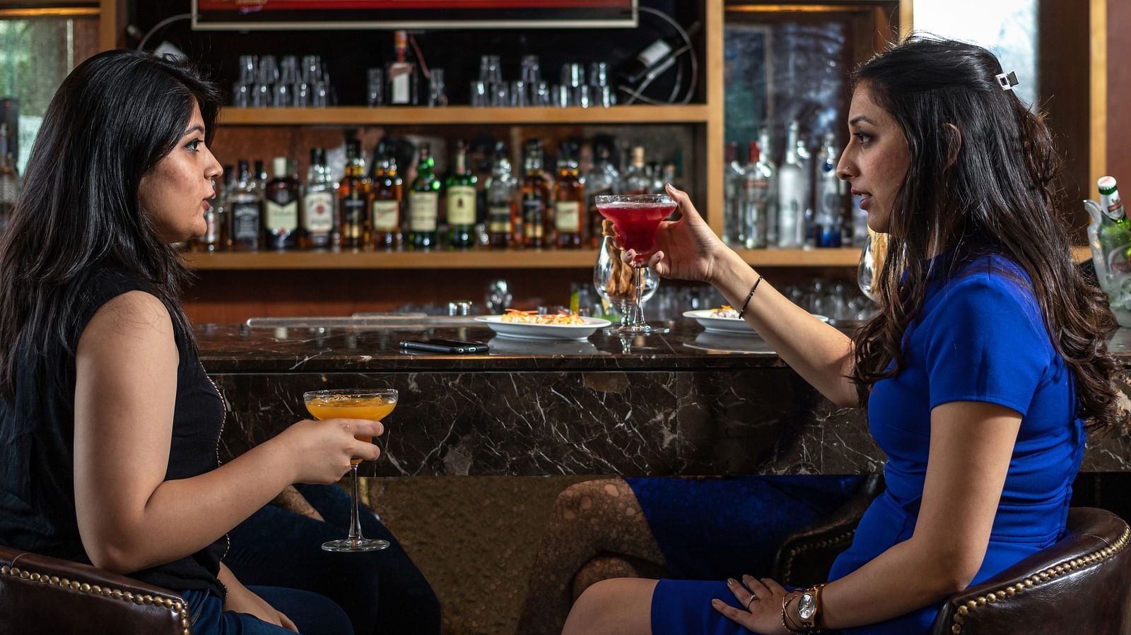 Two people enjoying the drinks in the bar at Golden Suites, Gurgaon
