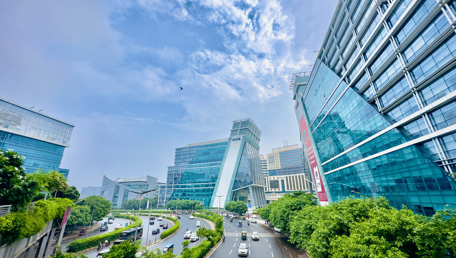 An overview of DLF Cyber City with buildings and trees and clouds in the background