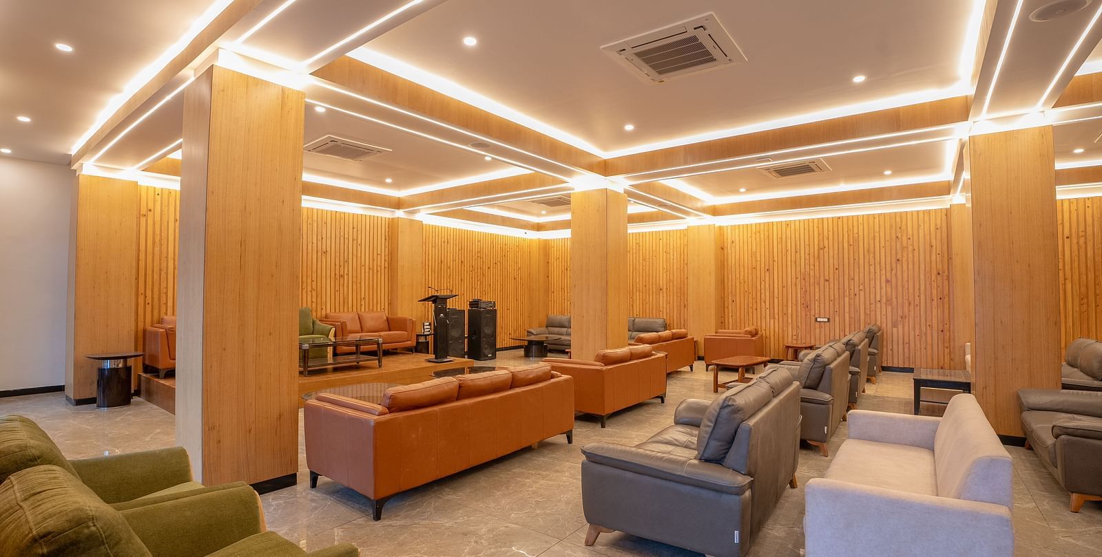 A shot of banquet hall at Summit featuring comfortable sofas of diffrent colours and a well lit surronding.