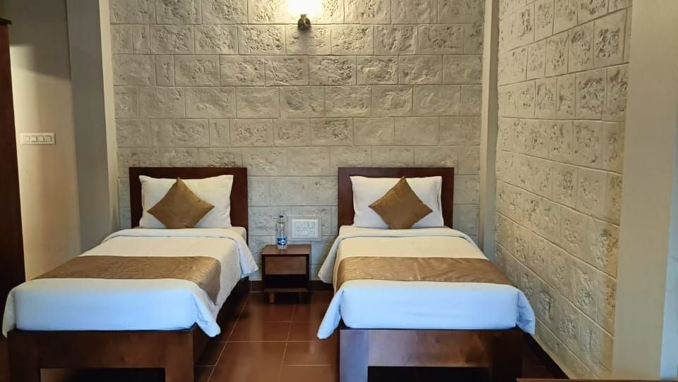 Deluxe Family Room at Woodstock Resorts, Coorg with twin beds, dining table, spacious seating, and elegant lighting.