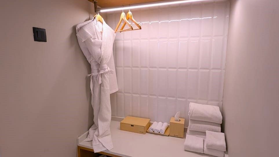 A view of a changing area at Swosti Premium Beach Resorts, Puri, featuring bathroom amenities such as towels and a bathrobe.