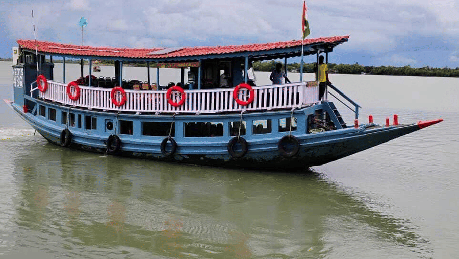 A boat featuring a red and blue canopy floating on the water under a cloudy sky at Hotel Sonar Bangla, Sundarban.