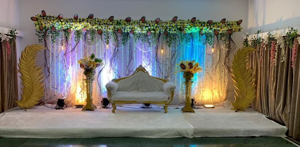 Floral stage setup with soft lighting and golden curtains, ideal for weddings and special events at Mayur Retreat.