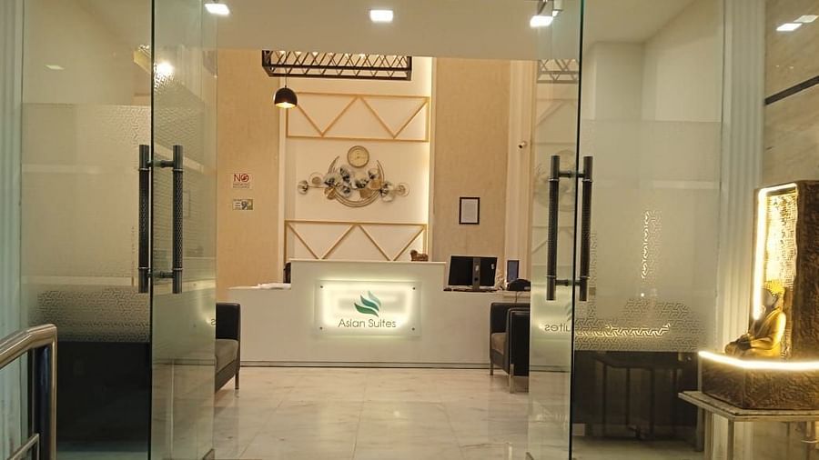 A modern entrance with glass doors and decorative wall panels leads into a brightly lit interior space - Asian Suites Cyber Park, Gurgaon