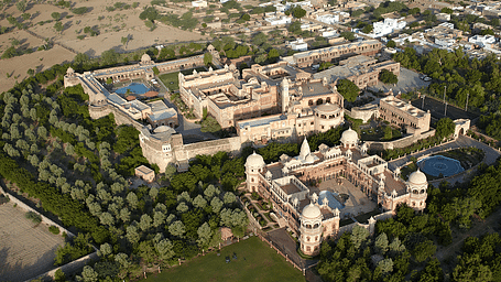 A drone shot of Khimsar Fort covered in lush green trees
