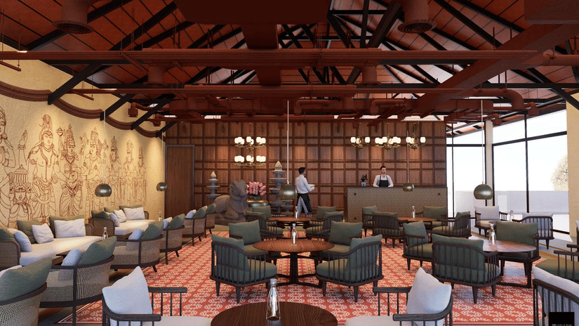Restaurant of MGM Paradise Resort, Kumbakonam featuring a reception desk, multiple sofa chairs with tables, attic style ceiling, and a view of the outdoor lawn. 