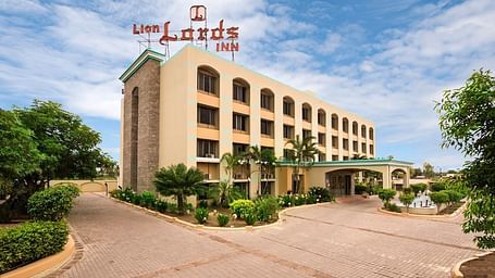 The front of a light-coloured building visible on a sunny day - Lion Lords Inn Rajula