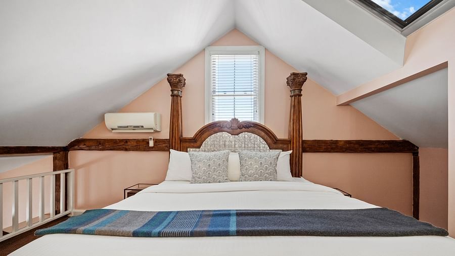A bedroom with sloped ceiling, skylights, and carved wooden bed at Hartstone Inn.
