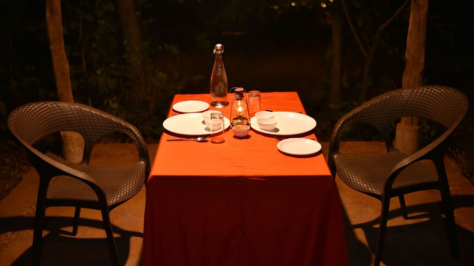 An intimate outdoor dining setting at Forest Escapes Koyna with a beautifully set table for two under the evening sky.