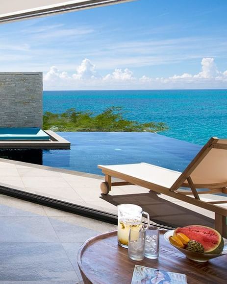 A private pool with lounge chairs, offering a clear view of the ocean and blue sky at Tamarind Hills Resort and Villas - Antigua.