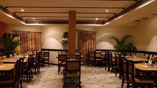 Side view of Akshara Restaurant with multiple chairs and modern interior - Jayaram Hotel, Pondicherry