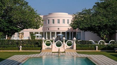 A facade image of Raj Mahal Palace with a pool in front