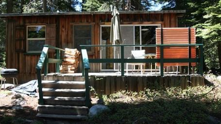 A rustic cabin with weathered wood siding and a slanted roof. - Kit Carson Lodge