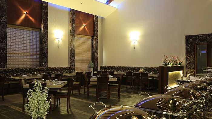A cosy and intimate seating area with decorative floral arrangements, creating a serene dining atmosphere. - Dhanalakshmi Srinivasan Hotels, Perambalur