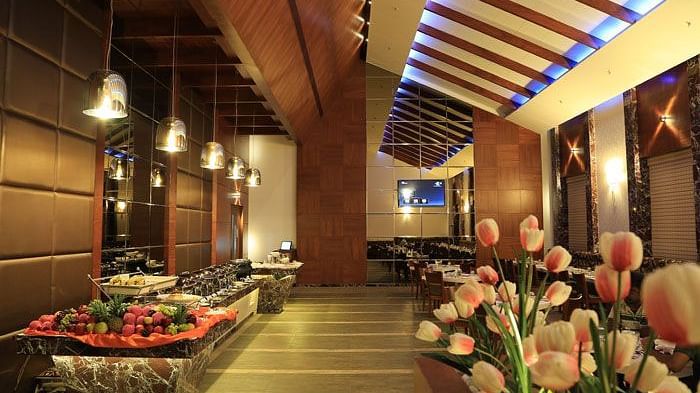 A beautifully decorated buffet counter with fresh flowers, soft lighting, and a luxurious dining ambience. - Dhanalakshmi Srinivasan Hotels, Perambalur