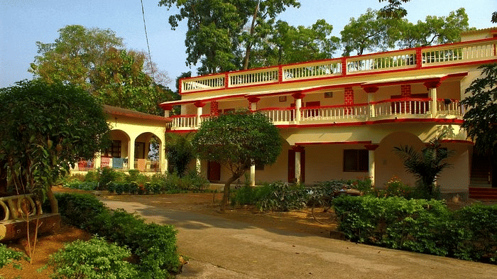 Hedges and trees are growing in a courtyard garden next to a multi-storey building at Khairi Resorts.