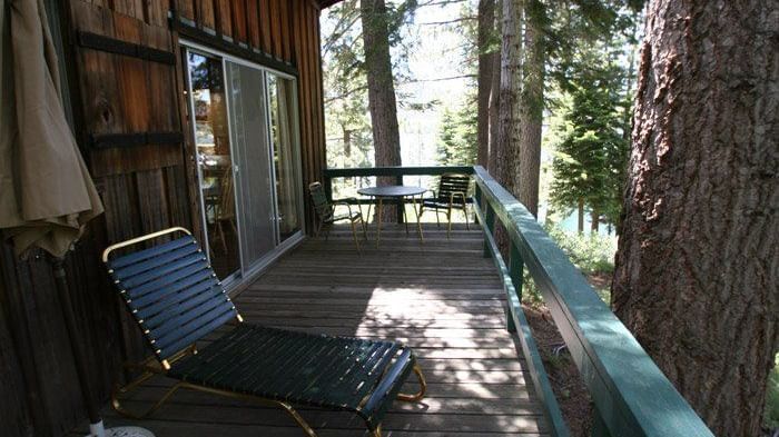 A rustic cabin deck with railings featuring a  lounge chair. - Kit Carson Lodge