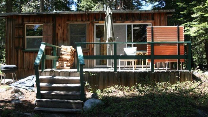 A rustic cabin with weathered wood siding and a slanted roof. - Kit Carson Lodge