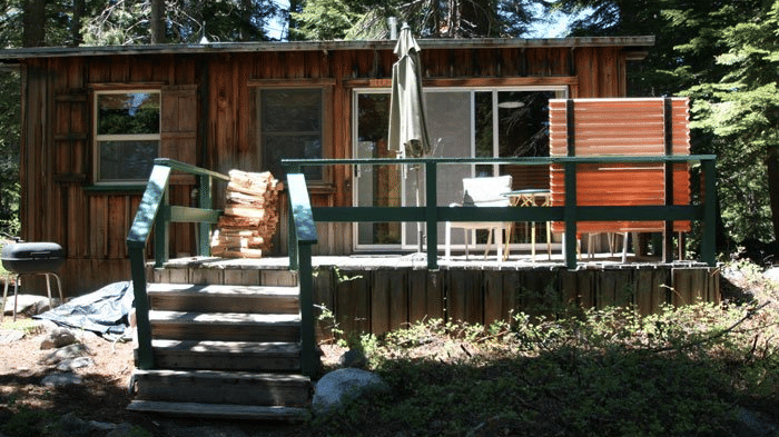 A rustic cabin with weathered wood siding and a slanted roof. - Kit Carson Lodge