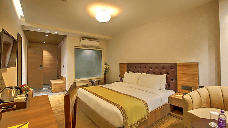 A comfortable double room with a padded brown headboard, a bedside lamp, and a coffee station setup on the wooden desk - Hotel 91 HUDA City Centre, Gurugram