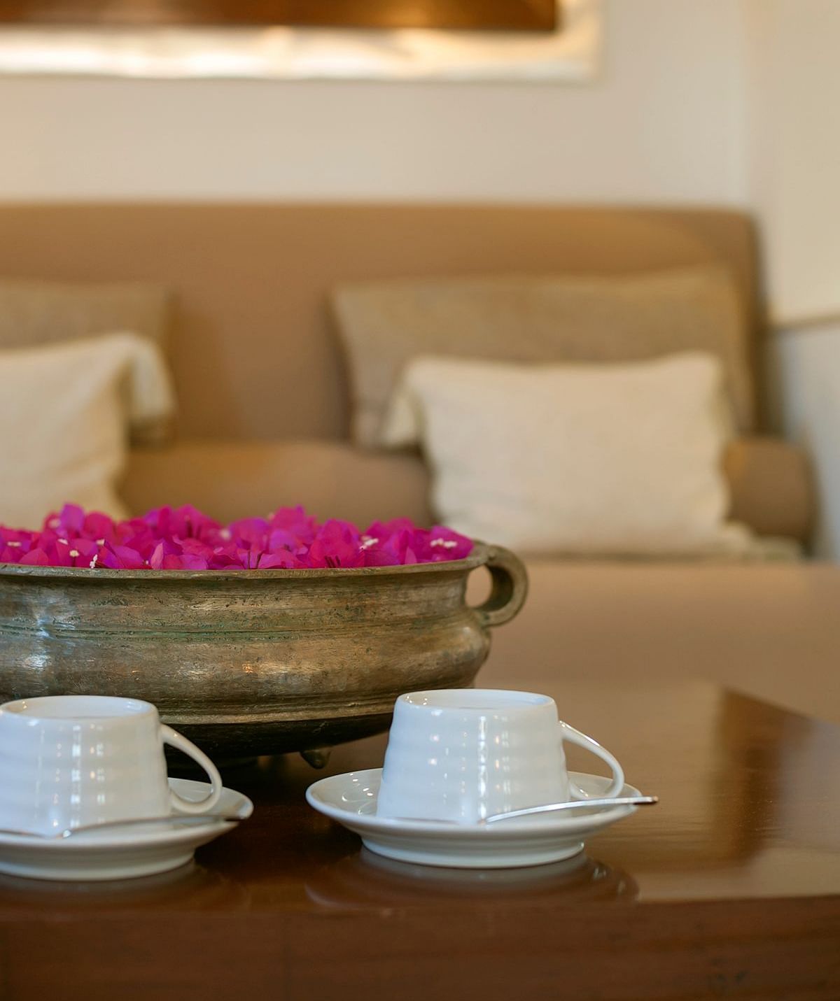 A tray of tea cups with flower petals in a calm living space - Shreyas Retreat