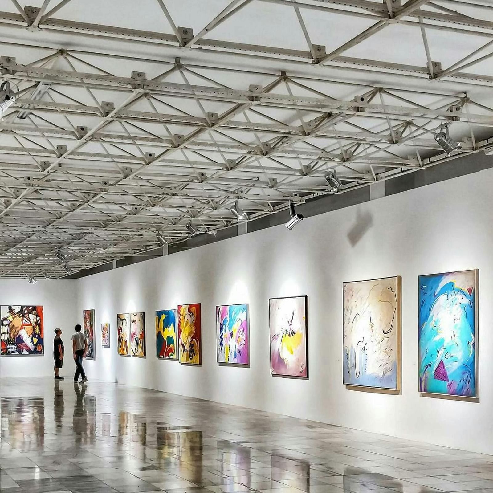 A well-lit room hosting an art exhibition, with pieces displayed on the walls