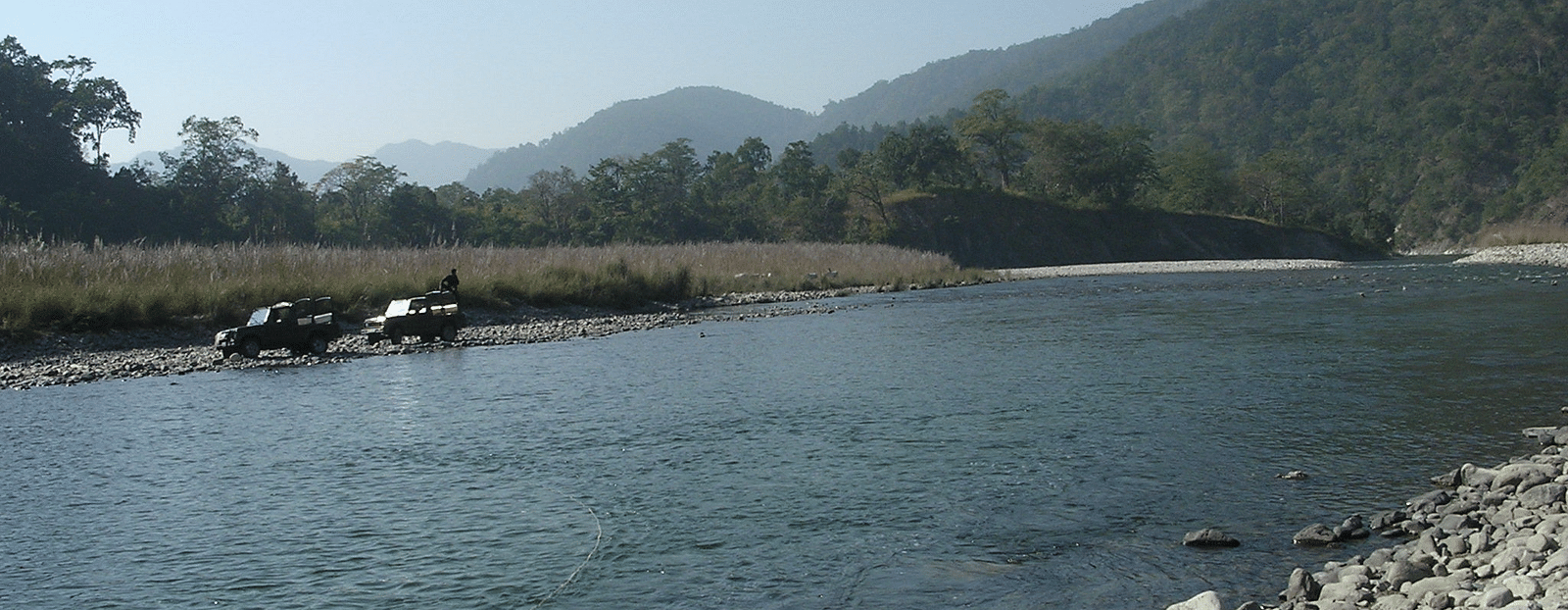 A picture featuring a river flowing through a lush landscape captured in the morning.