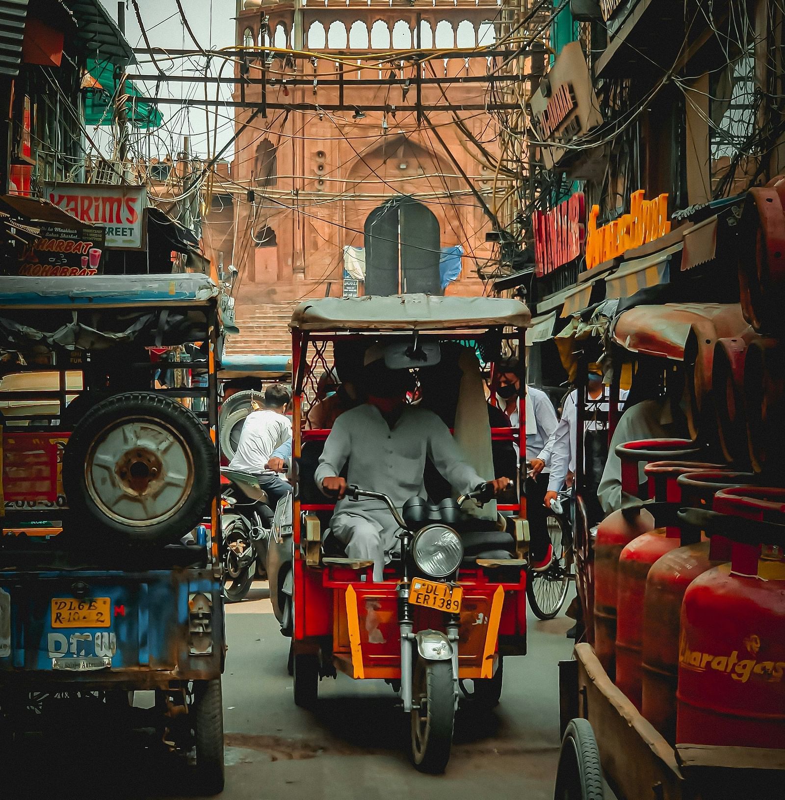 image of a busy street in delhi with the red fort in the bakground