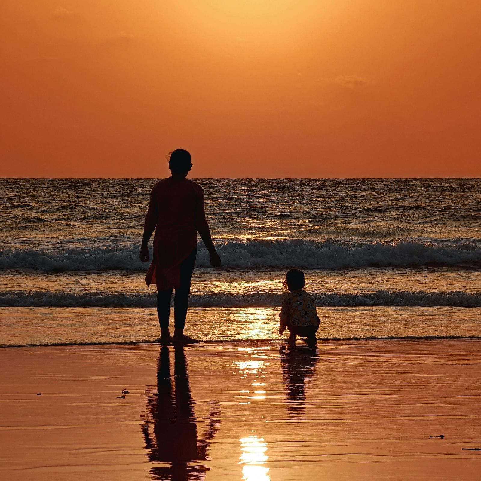 A woman with her child watching a scenic view of the sunset at Calangute Beach.
