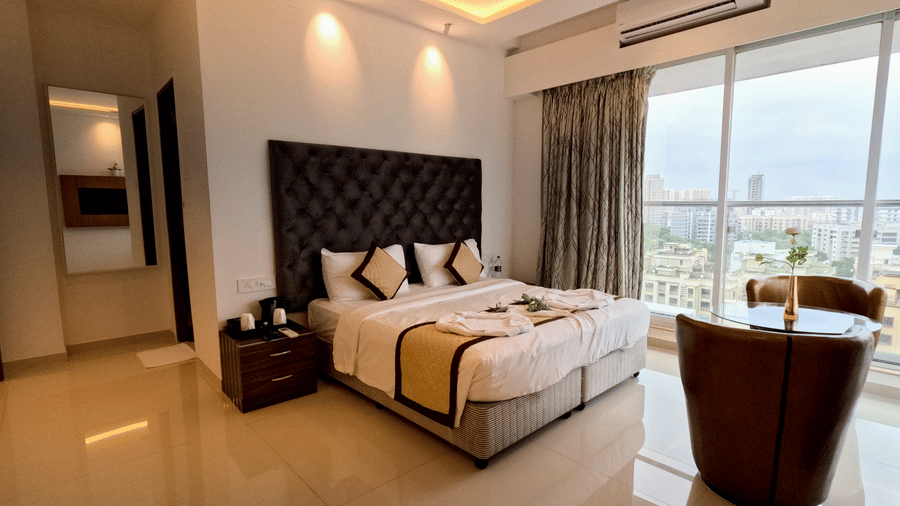 An image of the bedroom with twin beds with bedding and 2 cup-shaped arm chairs