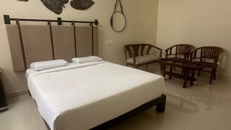 Bedroom with double bed, wall mirror, and ceiling fan at Hotel SRM Grands –Chennai.