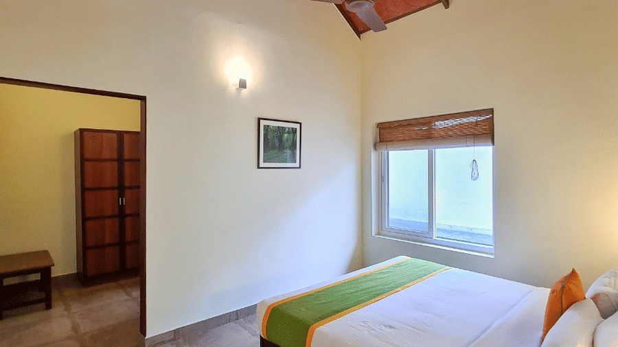 A bedroom features a four-poster bed and a window, offering natural light.- Abad Brookside Lakkidi, Wayanad