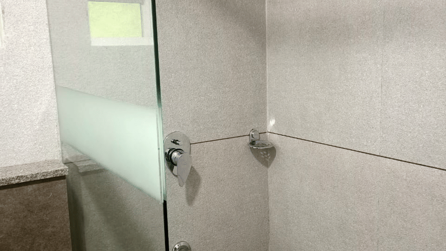 A shower stall features a shower head and exposed pipes.- Abad Brookside Lakkidi, Wayanad