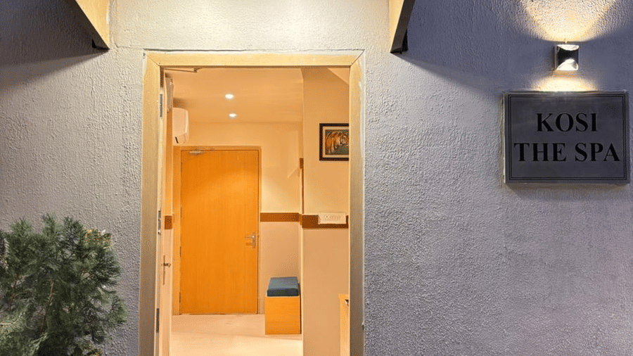 Entrance of the spa room at ABN Sarovar Portico, Jim Corbett featuring a nameplate which says, Koshi The Spa and next to it there is a door leading to the spa room.