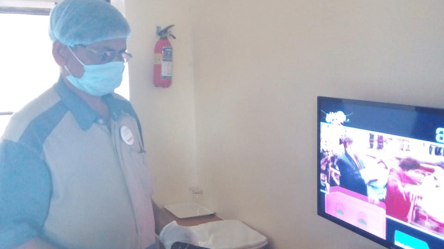 a staff member posing for a picture in front of a tv inside a room - VITS Hotels & Resorts
