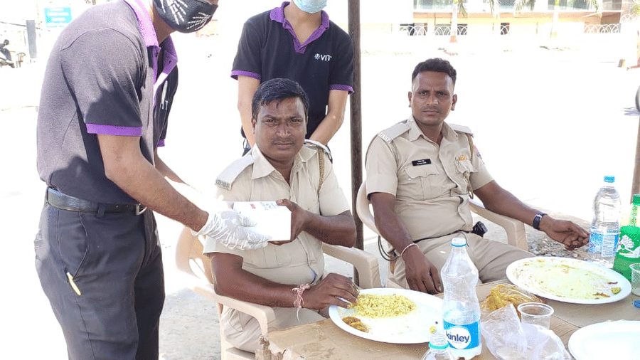 two staff members giving something to the police while posing for a picture - VITS Hotels & Resorts