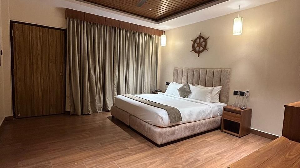 A wide angle shot of a room with wooden flooring and a king size bed with a side table | Arina Island Resort