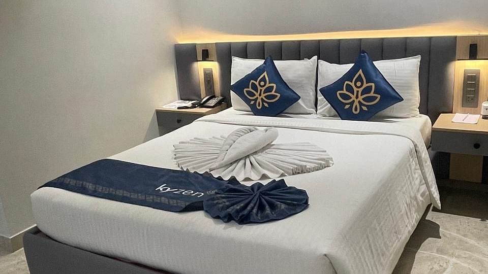 Brightly lit bedroom with a plush bed and decorative pillows at Hotel Kyzen HiTech City – Your Zenly Stay