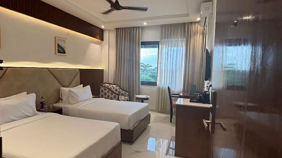A room with two single beds, framed wall art, fan at Trishvam Symphony, Krishnagiri.