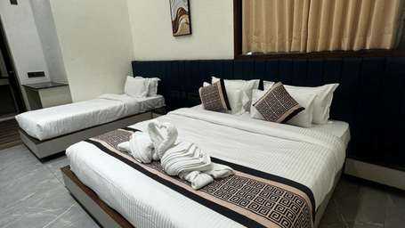 Premium double bed and a single bed with decorative runners and towel art - Lords Swastik Studio, Kodinar