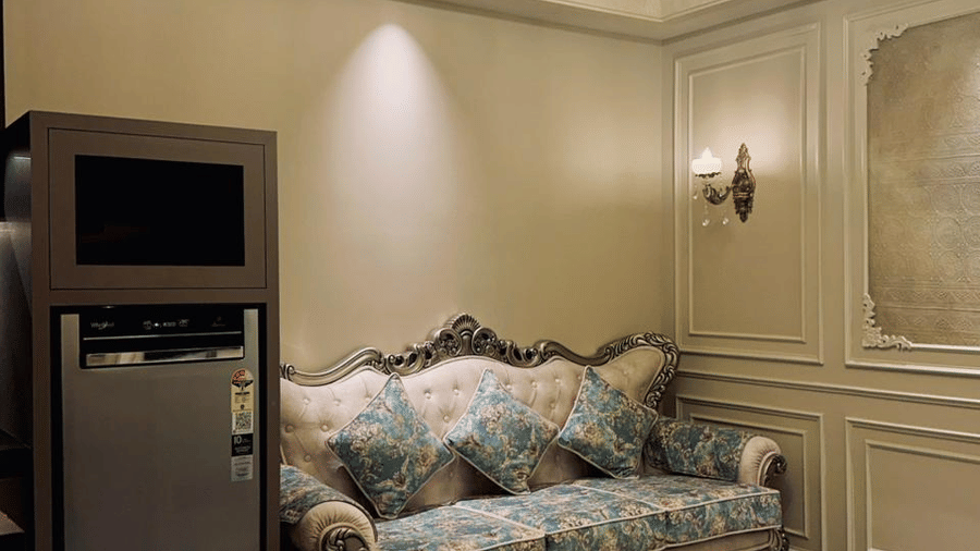 A plush couch kept beside a refridgerator in the living room of the Presidential Suite at F Hotels, Bengaluru.